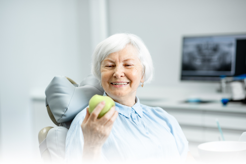 Older woman smiling eating an apple